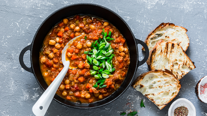 Black cooking pot full of chickpea and mushroom stew