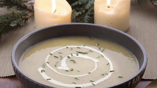 Cream of leek soup in a bowl with candles on a table