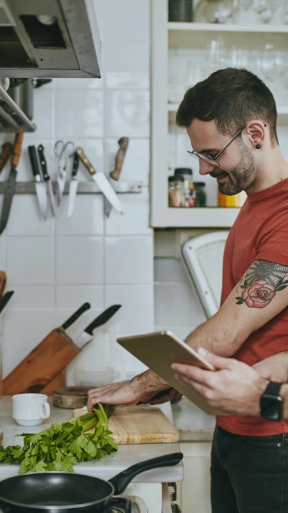 Two young men smiling and cooking together in a modern kitchen.