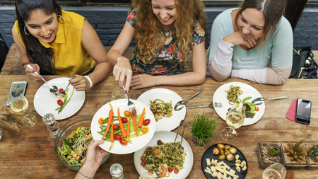 A group of women sharing a meal over a large wooden table